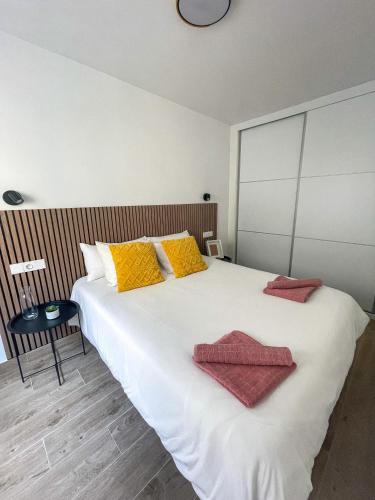 a bedroom with a large white bed with towels on it at H&H Suite El Mirlo in Granada