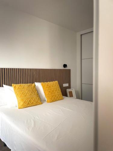 1 dormitorio con 1 cama blanca y 2 almohadas amarillas en H&H Suite El Mirlo en Granada