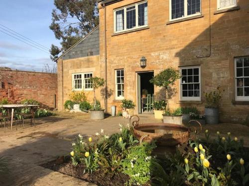 a brick building with a garden in front of it at Escape to Ash House 18th Century Manor in Somerset in Martock