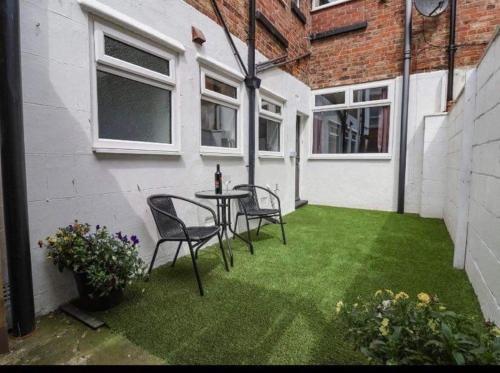 a patio with two chairs and a table on the grass at Rosie’s rest in Bridlington