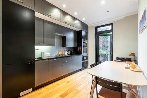 a kitchen with stainless steel appliances and a table at Beautiful two-bed abode Near King Cross in London