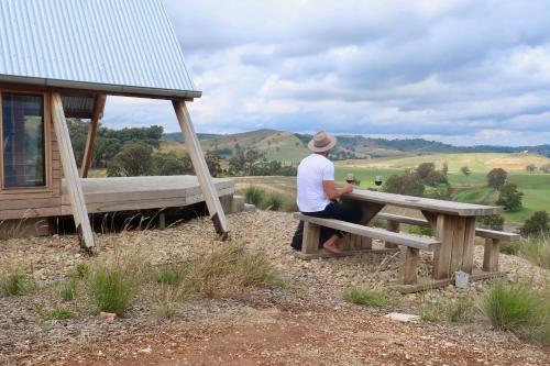 a man sitting at a picnic table with a view at Kimo Estate in Gundagai
