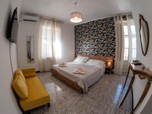 - une chambre avec un lit et une chaise jaune dans l'établissement I colori della Sicilia NOBLESSE, à Caltagirone