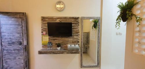 a mirror hanging on a wall with a television on it at Ana homestay in Negara