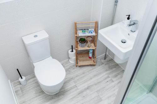 a white bathroom with a toilet and a sink at Beautifully Fab 3 bedroom 4 beds New home 8 guests Stretford Trafford in Manchester