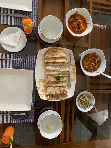 a table with plates of food and bowls of food at Aaradhya Nuwara Eliya in Nuwara Eliya