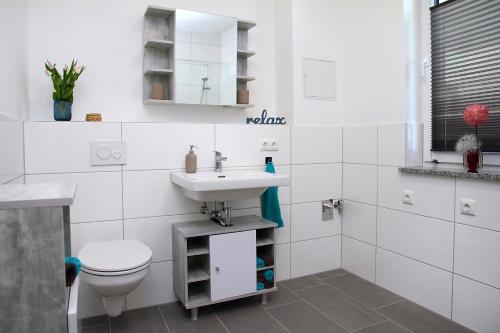 a white bathroom with a sink and a toilet at FeWo Varis in Röbel