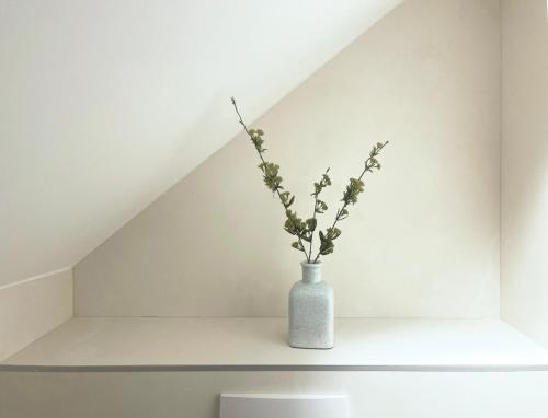 a white vase with flowers sitting on a shelf at Place Sainte Marguerite in Provins