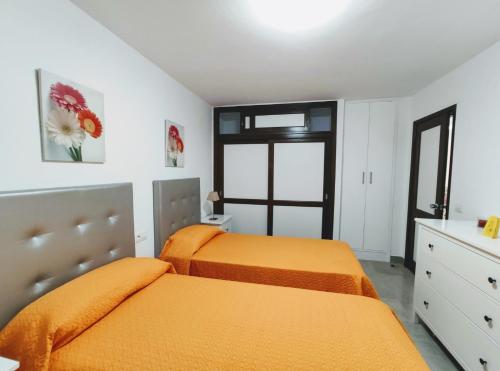 two beds in a bedroom with orange sheets at Casa Royal Los Cristianos Center in Los Cristianos