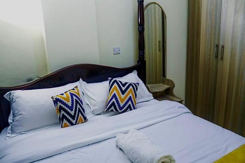 a bed with three pillows on top of it at Tashma Airbnb Apartment in Nairobi