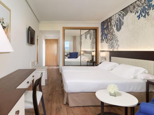 a hotel room with a bed and a desk and a room at H10 Salauris Palace in Salou