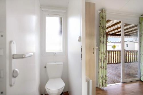 a bathroom with a toilet and a door with a porch at Bungalow T3 I - 15 Min From Nazaré in Pataias