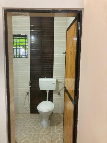 a bathroom with a white toilet in a room at Hotel Khushi Waves in Arpora