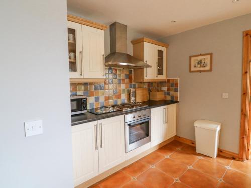 a kitchen with white cabinets and a stove top oven at 14 Sneem Leisure Village in Sneem