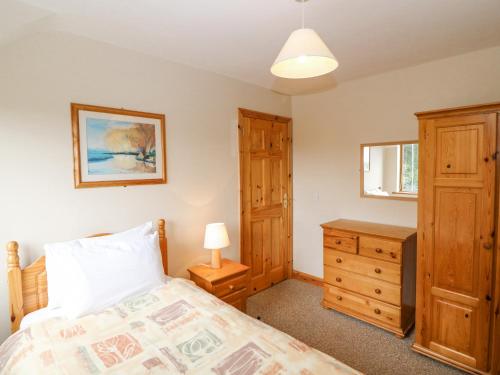 a bedroom with a bed and a wooden dresser at 14 Sneem Leisure Village in Sneem