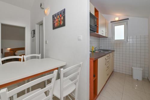 a kitchen with a counter and a table and chairs at Seagull Pool Apartments & Studios in Novalja