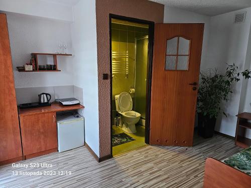 a bathroom with a toilet and a yellow door at Pokoje u Joli Polańczyk in Polańczyk