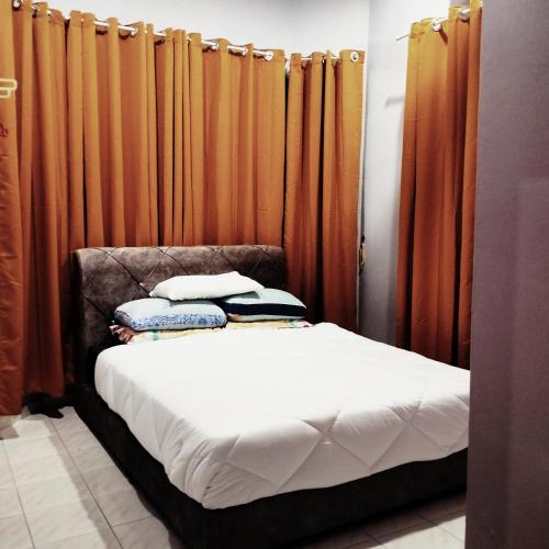 Bett in einem Zimmer mit orangefarbenen Vorhängen in der Unterkunft Rezqrich Villa Homestay 1 in Kampung Degong