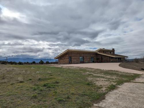 a brick building on a field with a cloudy sky at Alojamiento rural de lujo en Pedraza-Tejadilla in Valleruela de Pedraza