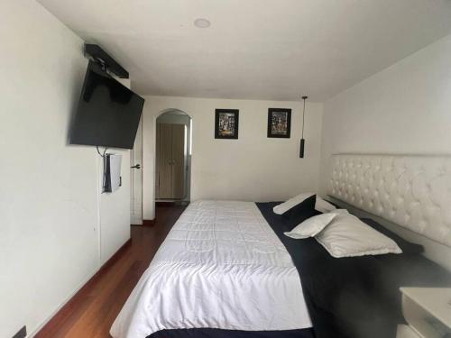 um quarto com uma grande cama branca e 2 almofadas em Galeras 103 em Bogotá