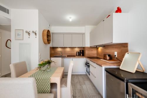 une cuisine avec des placards blancs et une table avec une salle à manger dans l'établissement Le Jasmin, à Nice