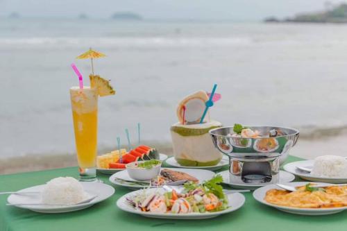 a table with plates of food and a drink at Coconut Beach Resort, Koh Chang in Ko Chang