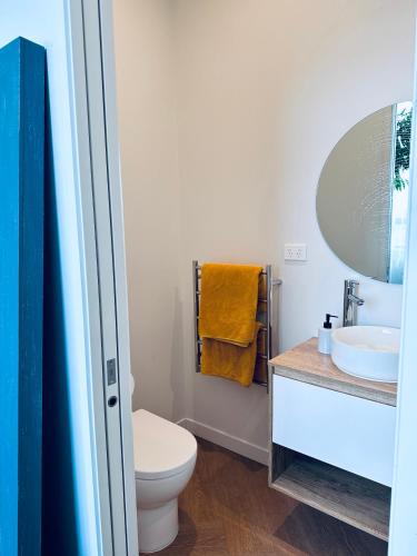a bathroom with a toilet and a sink and a mirror at Stylish Industrial Holiday House in Pakuranga Free Wifi Netflix in Auckland