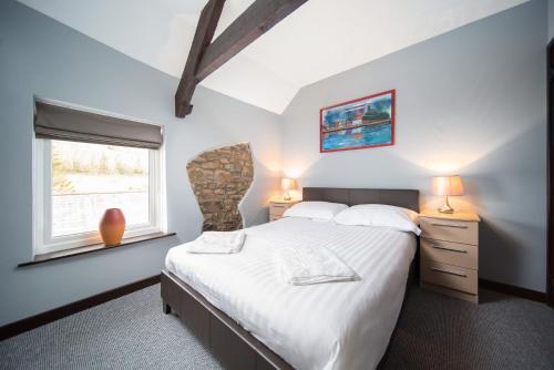 um quarto com uma cama grande e uma janela em Royd Cottage at Lower Aylescott em West Down