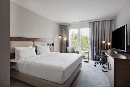 a hotel room with a bed and a television at Courtyard by Marriott Munich City East in Munich