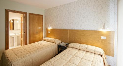 Una habitación de hotel con dos camas y un espejo. en Hostal Bezana, en Burgos