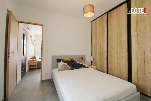 une chambre avec un lit blanc avec une tête de lit en bois dans l'établissement LA PASTISSIERE BIS - 4 COUCHAGES, à Carry-le-Rouet