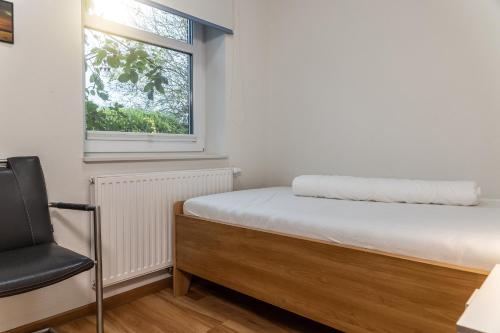 ein kleines Schlafzimmer mit einem Bett und einem Stuhl in der Unterkunft 50017 Haus Silbermöwe in Harlesiel
