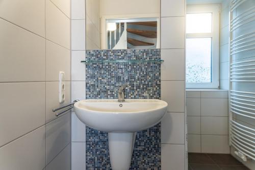 a bathroom with a white sink and a mirror at 50017 Haus Silbermöwe in Harlesiel