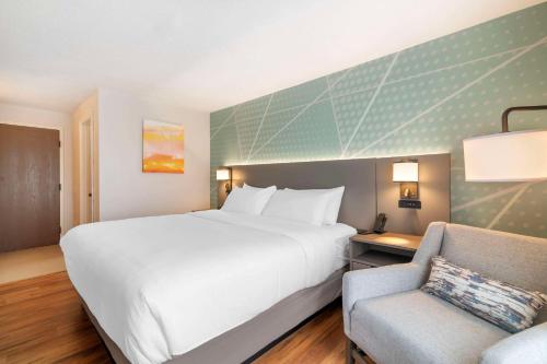 a hotel room with a large bed and a chair at Comfort Inn South Portland Airport in South Portland