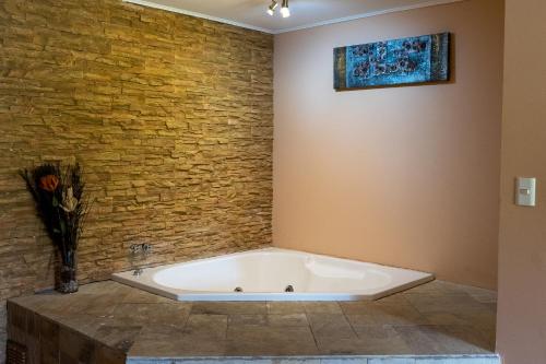Suite Complejo Turistico Antu de Quillón في كيلون: حوض استحمام في غرفة بجدار من الطوب