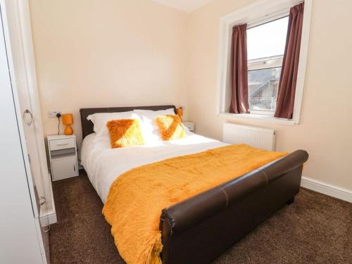Un dormitorio con una cama con almohadas naranjas y una ventana. en Stella’s secret, en Bridlington