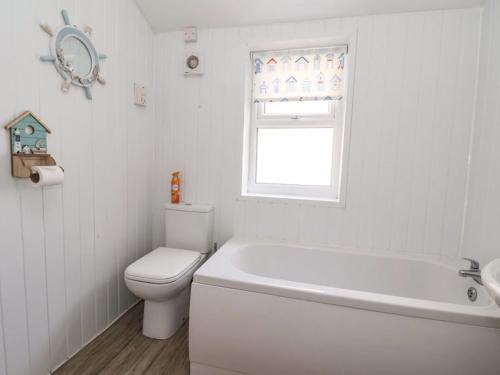 a bathroom with a toilet and a tub and a window at Stella’s secret in Bridlington