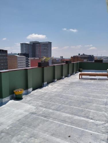 a rooftop with a bench and a view of a city at @Derricks Luxury Apartments 2 in Johannesburg