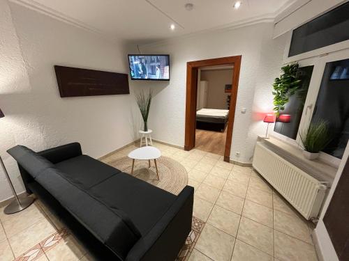 a living room with a black couch and a flat screen tv at Pension am Schloss in Schwerin