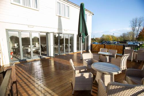 a deck with chairs and a table and a building at The Bridge House; BW Signature Collection in Ferndown