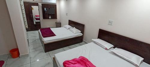 a bedroom with two beds and a mirror at Hotel Shri Krishna Palace in Ujjain