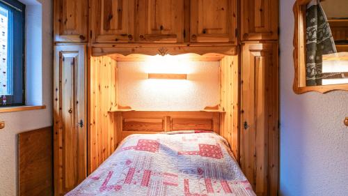a small bedroom with a bed in a wooden cabin at Grande Neige 39 - pied des pistes 4 pers in Morillon