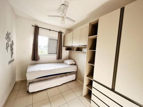 ein kleines Zimmer mit 2 Betten und einem Fenster in der Unterkunft Confortável apartamento perto de praias - Bertioga in Bertioga