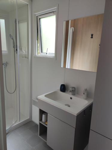 une salle de bain blanche avec un lavabo et une douche dans l'établissement Mobil home 3 ch 6 pers Camping Mayotte, à Biscarrosse