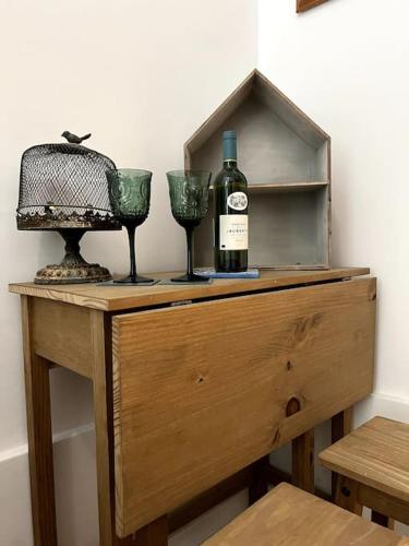 a wooden table with a bottle of wine and two glasses at Rabat Pied-a-terre in Rabat