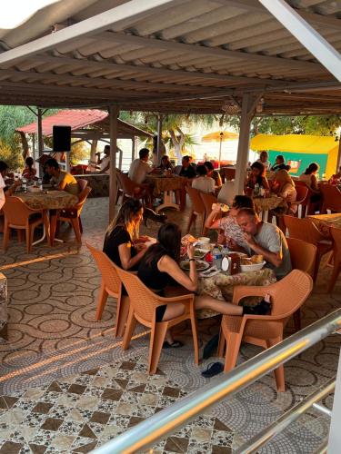 um grupo de pessoas sentadas em mesas em um restaurante em Mavi Cennet Camping&Pansiyon em Kızılot