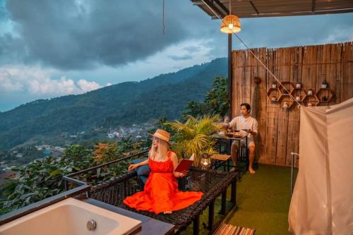 a woman in a red dress sitting on a balcony with a laptop at ฮิมสวน โฮมสเตย์ Him suan homestey in Ban Thung Phan Ha