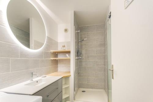 a bathroom with a sink and a shower with a mirror at Appartement vue Mer in Saint-Cast-le-Guildo