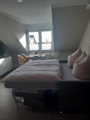 a bedroom with a bed and a table and windows at Neumühler Hof- Gemütliche Wohnung "Lenia" Parkplätze und Kongresshalle in der Nähe in Schwerin