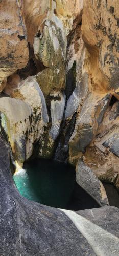 a rock cave with a pool of green water at Sunset view hill jabal shams in Misfāh